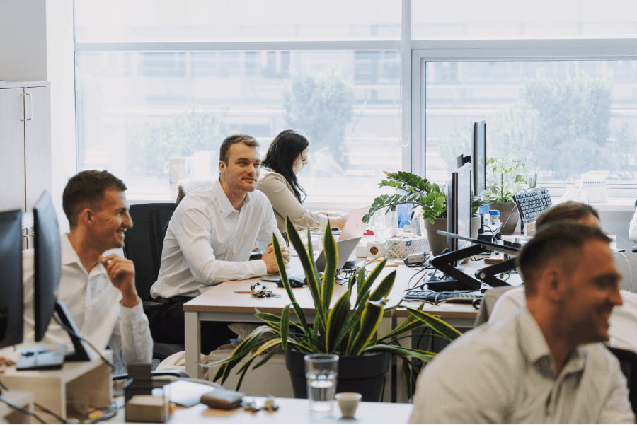 A group of people working in a busy office with Mr. Šimeček in the middle